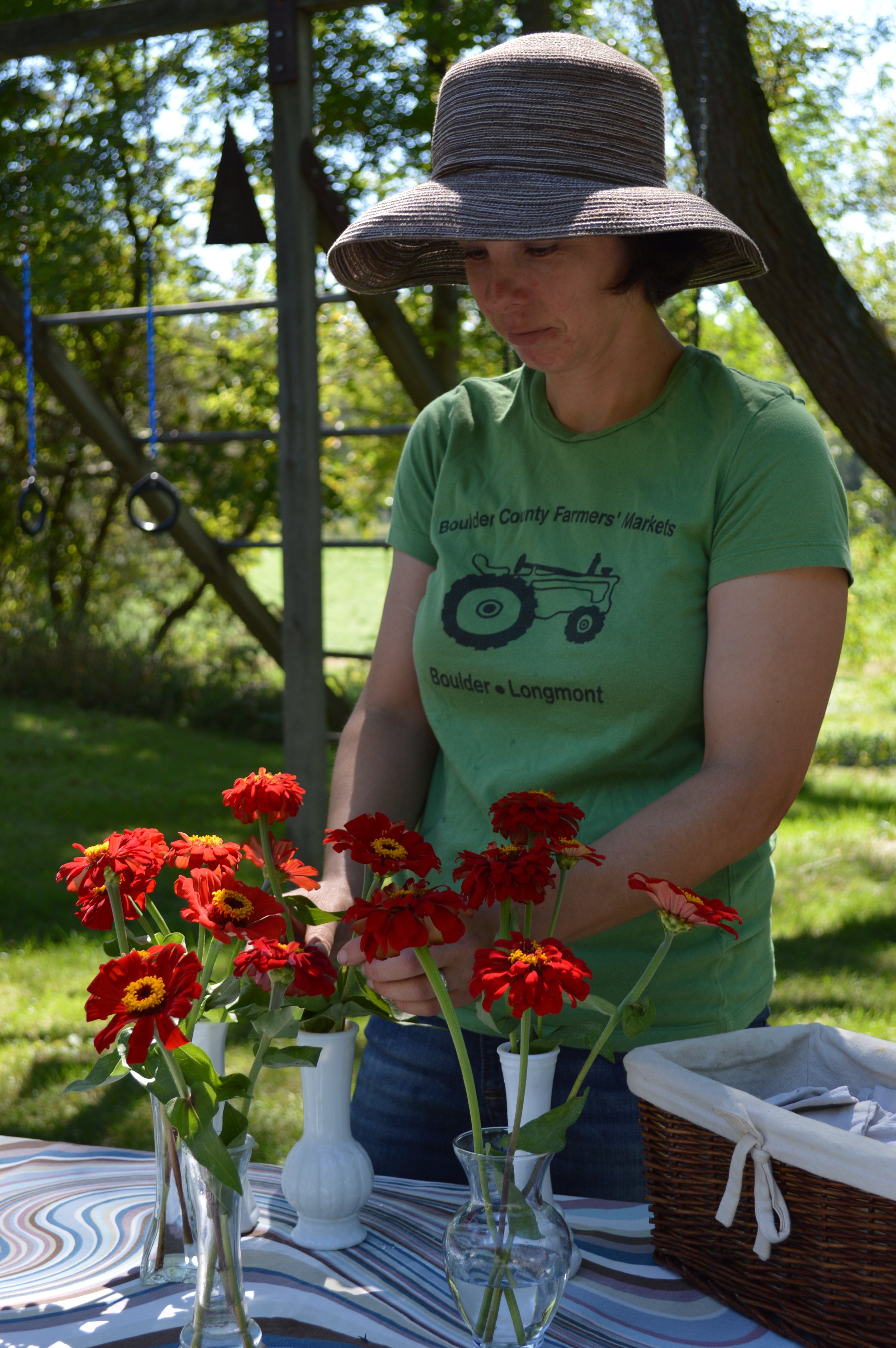Female farmer arranging zinnias in vases outside
